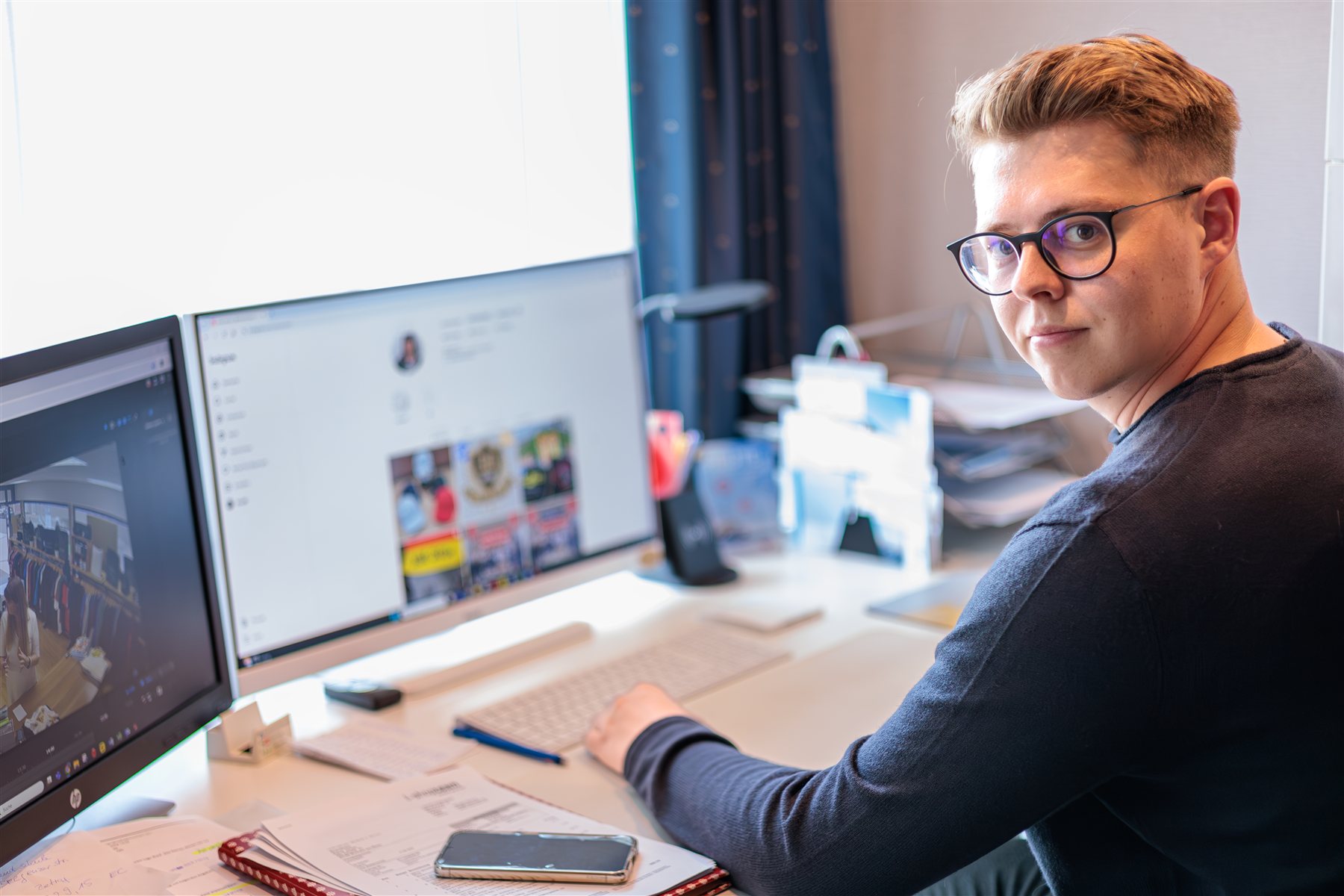 Mann mit Brille an einem Arbeitsplatz mit zwei Bildschirmen
